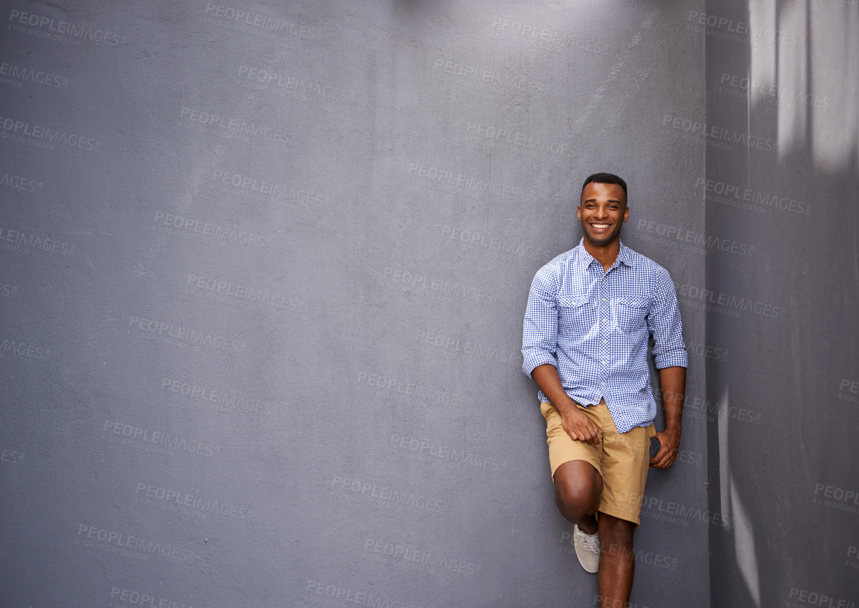 Buy stock photo A handsome young man leaning against a blue/gray wall