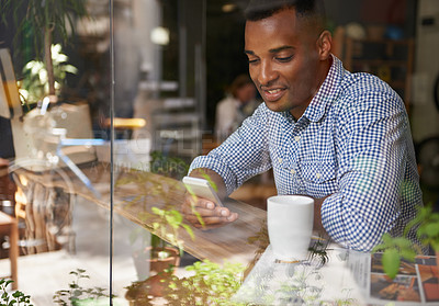 Buy stock photo Coffee, window and man with smartphone at cafe for social media, communication and networking. Person, smile and technology in restaurant for texting, message and scrolling on website online