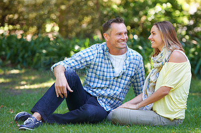 Buy stock photo Relax, chat and couple with smile on grass for summer romance, trees and fun outdoor date. Love, mature man and happy woman in garden with morning sunshine, talking and marriage bonding in nature.