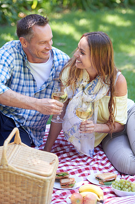 Buy stock photo Couple, picnic and wine on date in outdoor nature, love and romance in relationship on weekend. Alcohol, conversation and people to relax in countryside, adventure and grass for care on vacation