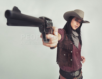 Buy stock photo Cowgirl, portrait and gun pointing or western costume with confidence on white background, weapon or mockup space. Female person, face and revolver in studio or old west Texas, accessories or bandit