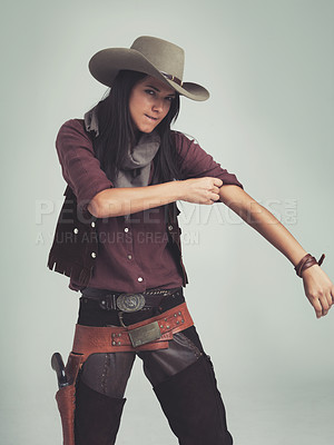 Buy stock photo Tough, woman and cowboy portrait with fashion outfit, in Texas as cowgirl and leather belt. Angry face, rolling up sleeve and ready to fight with gun in holster and comic on a grey background studio