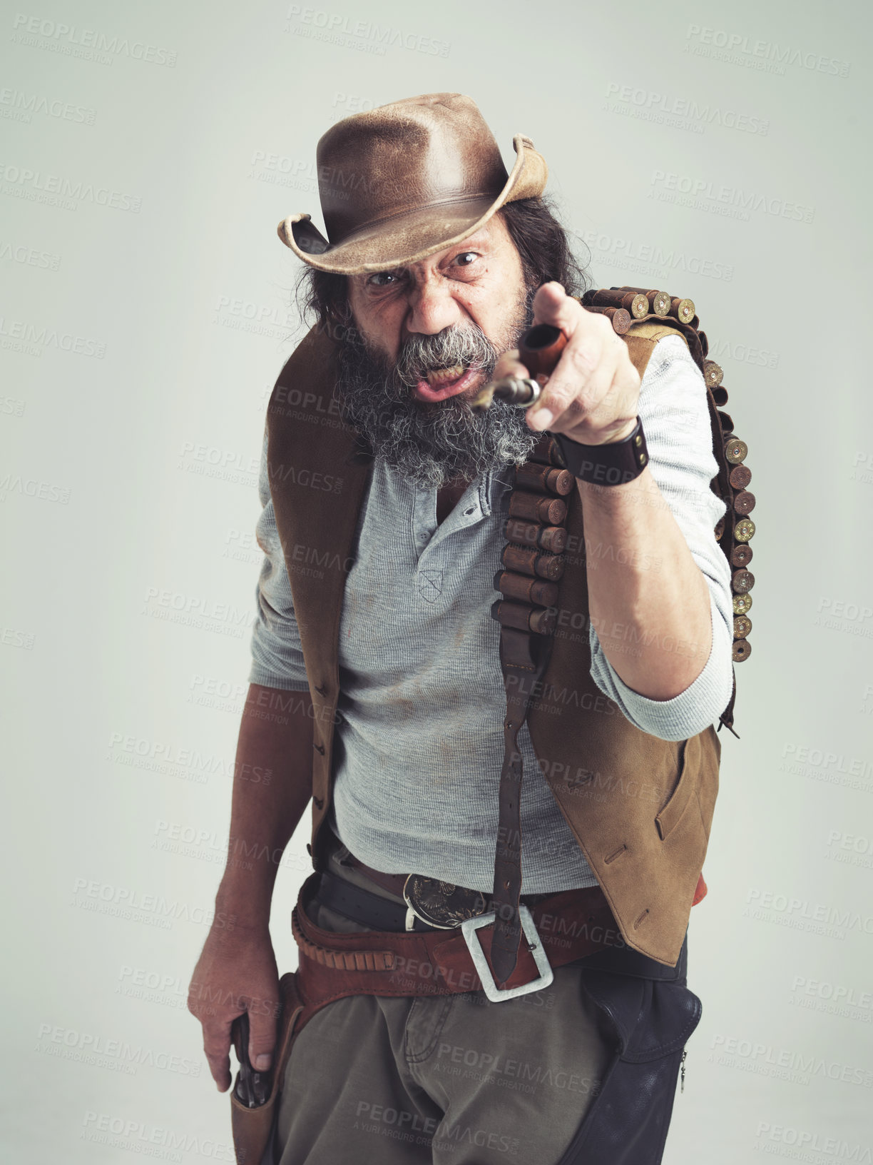 Buy stock photo Senior cowboy, point and angry face at studio, costume and holster for western portrait looking scruffy. Old man, sheriff hat and dirty male for texas, grey background and annoyed gesture for outlaw