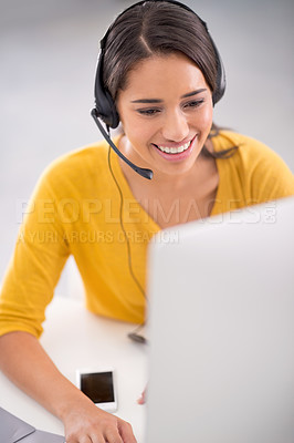 Buy stock photo Shot of a young customer service representative wearing a headset while sitting by her computer