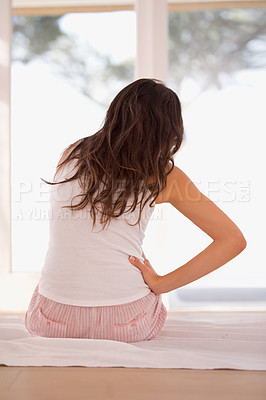 Buy stock photo Woman, backache and pain on bed, fibromyalgia and injury in home for discomfort in menstrual issues. Female person, back and inflammation on joints in bedroom, muscle strain and hurt by bad posture