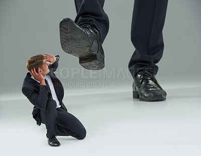 Buy stock photo Cropped view of a businessman crouched as a giant shoe comes down on him