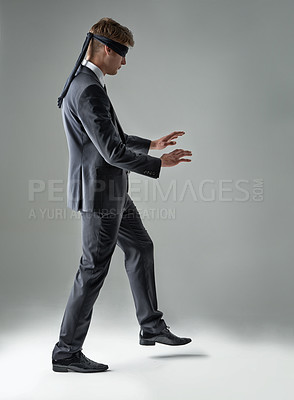 Buy stock photo A blindfolded businessman trying to walk across the room