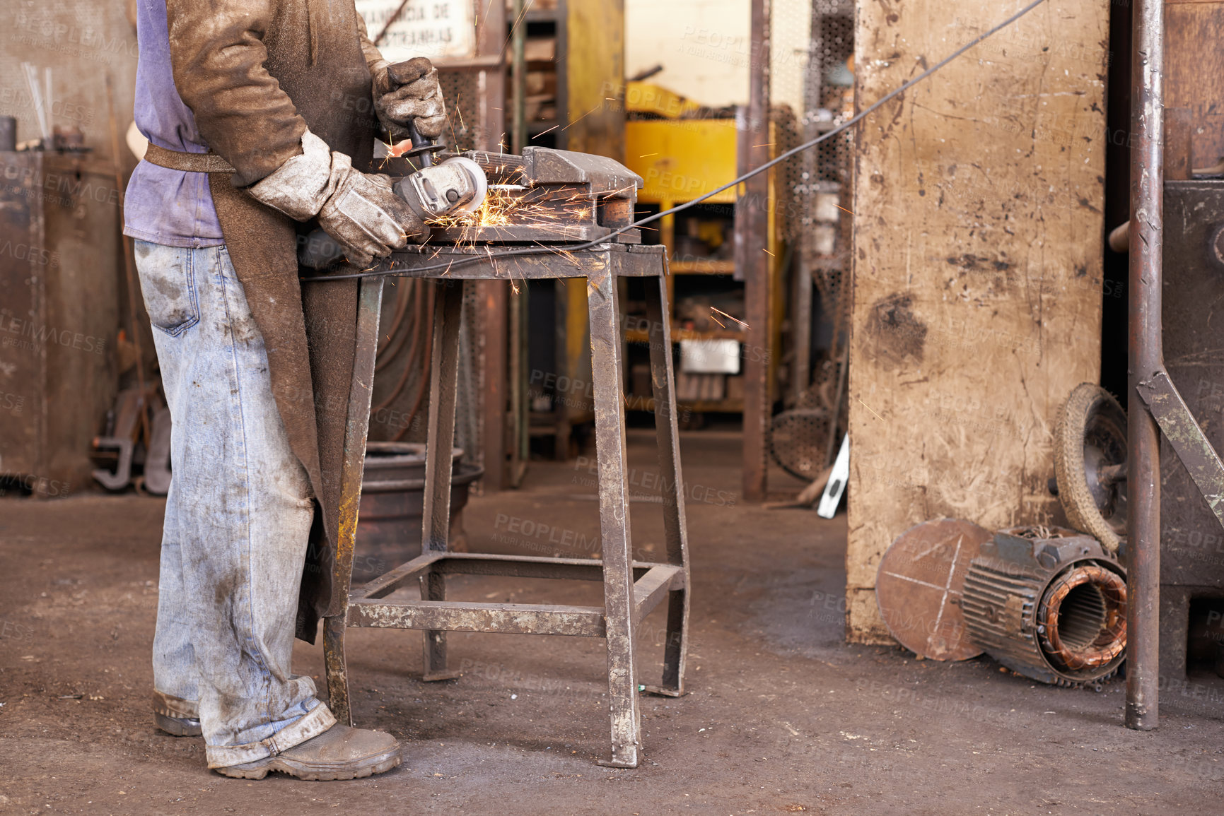 Buy stock photo A man grinding a piece of metal in a workshop