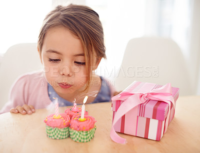 Buy stock photo Cupcakes, blowing candles and girl with birthday, kid and gift with happiness, candy and home. Childhood, celebration and excited with dessert or present with party or box with wow, sweet or surprise
