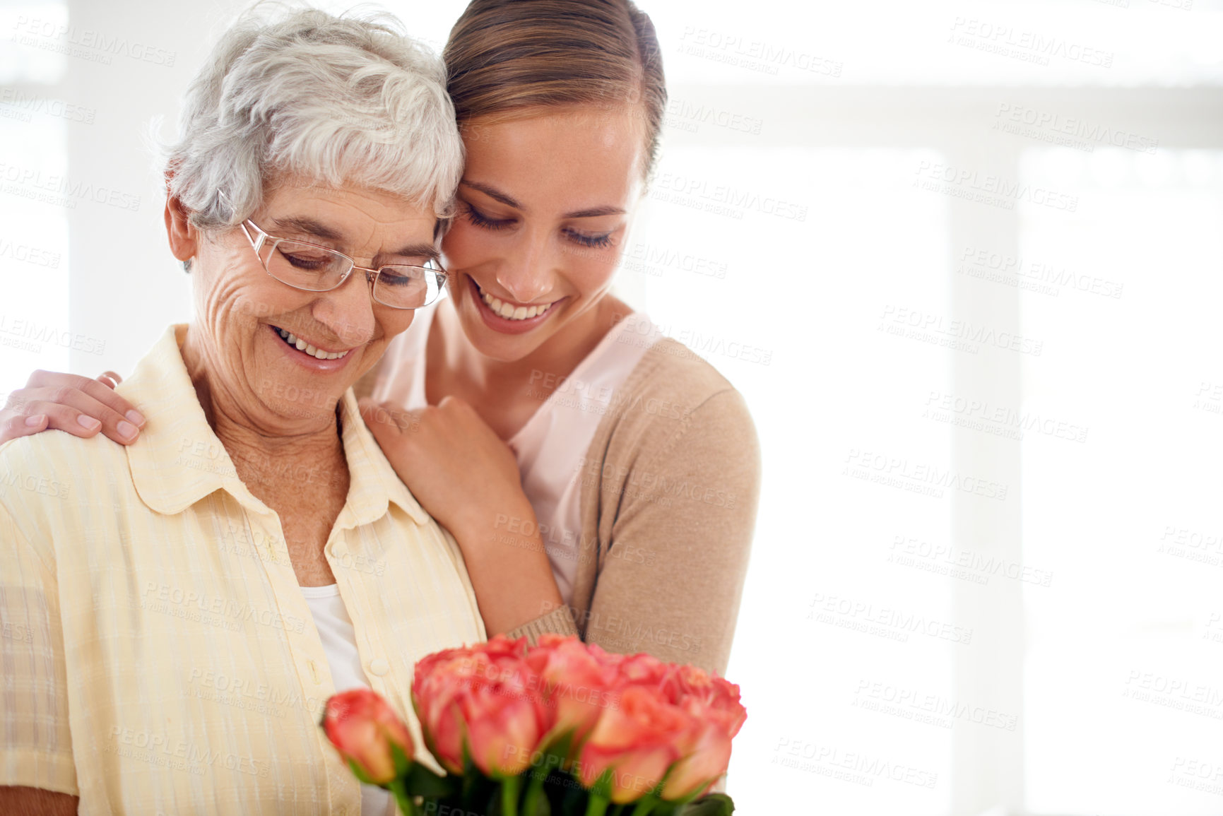 Buy stock photo Senior woman, daughter and hug with flowers, present and care for love, bonding or reunion at family home. People, elderly mom and mothers day celebration for connection, gift or bouquet in apartment