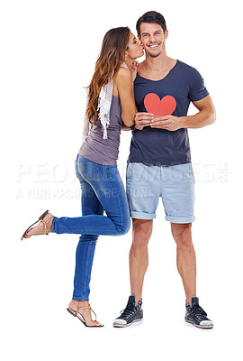 Buy stock photo Full-length studio shot of a young woman kissing her boyfriend who is holding a heart