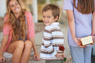 Buy stock photo Mothers day, surprise and home with happy children, flowers and back together with a smile, gift and holiday. Family, lounge and mom excited on living room sofa with present and floral plant in house
