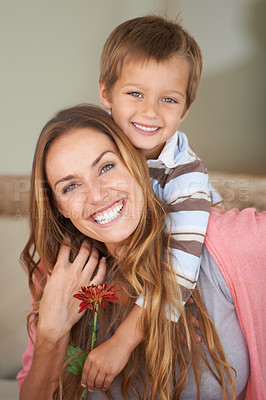 Buy stock photo Portrait, mother and son with smile on mothers day with piggyback, bonding and together inside. Happy woman, boy and laugh with flower, hug and love for playful weekend in family home in Canada