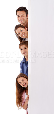 Buy stock photo Studio shot of a happy family peeking out from behind a tall placard