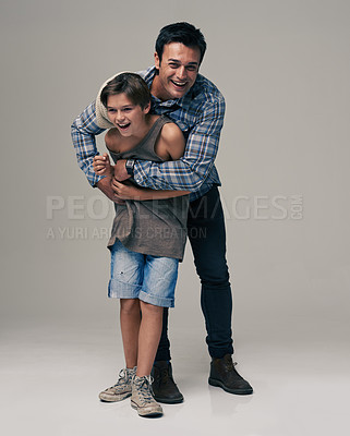 Buy stock photo Happy father, portrait and child laughing with hug for love, care or support in fashion on a gray studio background.  Dad playing with son or kid in happiness for parenting or bonding on mockup space