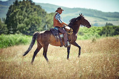 Buy stock photo Shot of a mature man riding a horse in a field