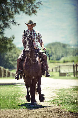 Buy stock photo Cowboy, summer and man riding horse with saddle on field in countryside for equestrian training. Nature, western and rodeo with mature horseback rider on animal at ranch outdoor in rural Texas