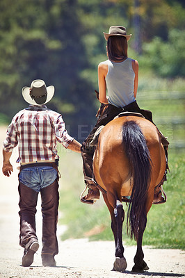 Buy stock photo Back of woman, cowboy or horse riding on countryside farm as equestrian for training, sport or learning. Walking, teaching or people in Texas, outdoor environment or stable for practice on saddle