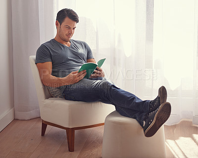 Buy stock photo Handsome man, relax and reading with book on chair in living room for story, literature or novel at home. Happy male person or young adult with smile for information, knowledge or learning in leisure