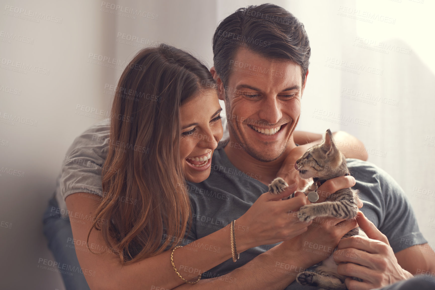 Buy stock photo Couple, kitten and smile in home on sofa with hug for love, bonding or care for pet in living room. People, man and woman with kindness, embrace and excited for baby cat in lounge for animal adoption