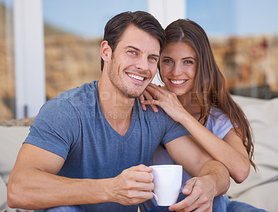 Buy stock photo Shot of an affectionate young couple relaxing on the patio with coffee