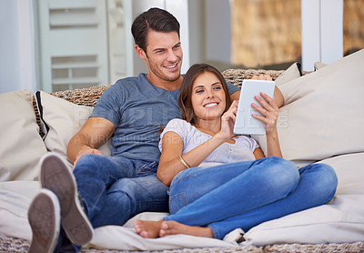 Buy stock photo Happy couple, relax and sofa with tablet for browsing movie, social media or entertainment at home. Man and woman lying with smile on technology for online streaming, series or show in living room