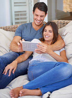 Buy stock photo Happy couple, hug and sofa with tablet for entertainment, movie or social media at home. Man and woman lying in relax with smile on technology for online streaming, series or show in living room