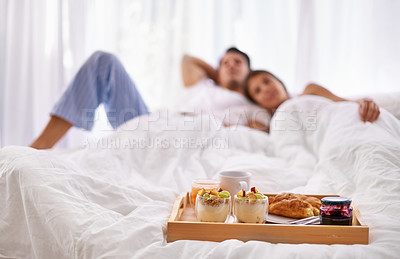 Buy stock photo Breakfast food, bed and couple in a bedroom at home with blurred background. Fruit, house and relax woman and man together with love and marriage care for valentines day feeling comfortable 