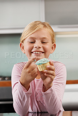 Buy stock photo Shot of an adorable little girl tasting a delicious cupcake
