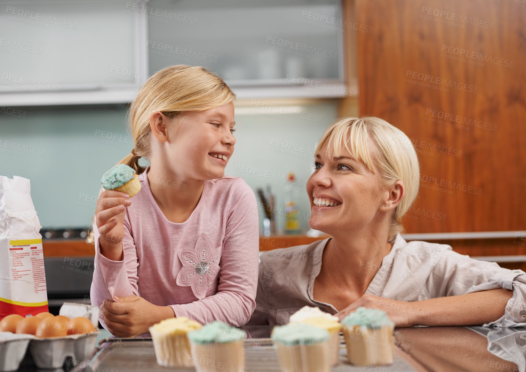 Buy stock photo Happy, mom and child with cupcake in kitchen and learning about baking together in home to relax. Family, bonding and kid smile with mother, excited for eating cake, sweets or enjoy food in house