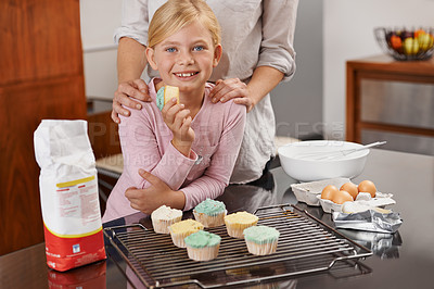 Buy stock photo Shot of an adorable little girl and her mom showing off the results of their baking