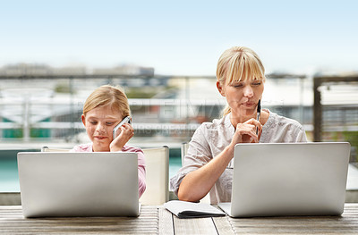 Buy stock photo Shot of a young girl and her mother using laptops side by side