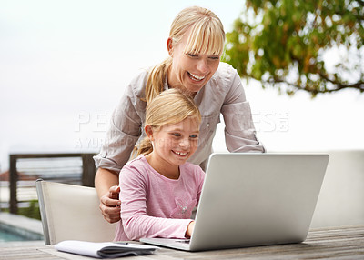 Buy stock photo Shot of a young girl using a laptop while her mother looks on
