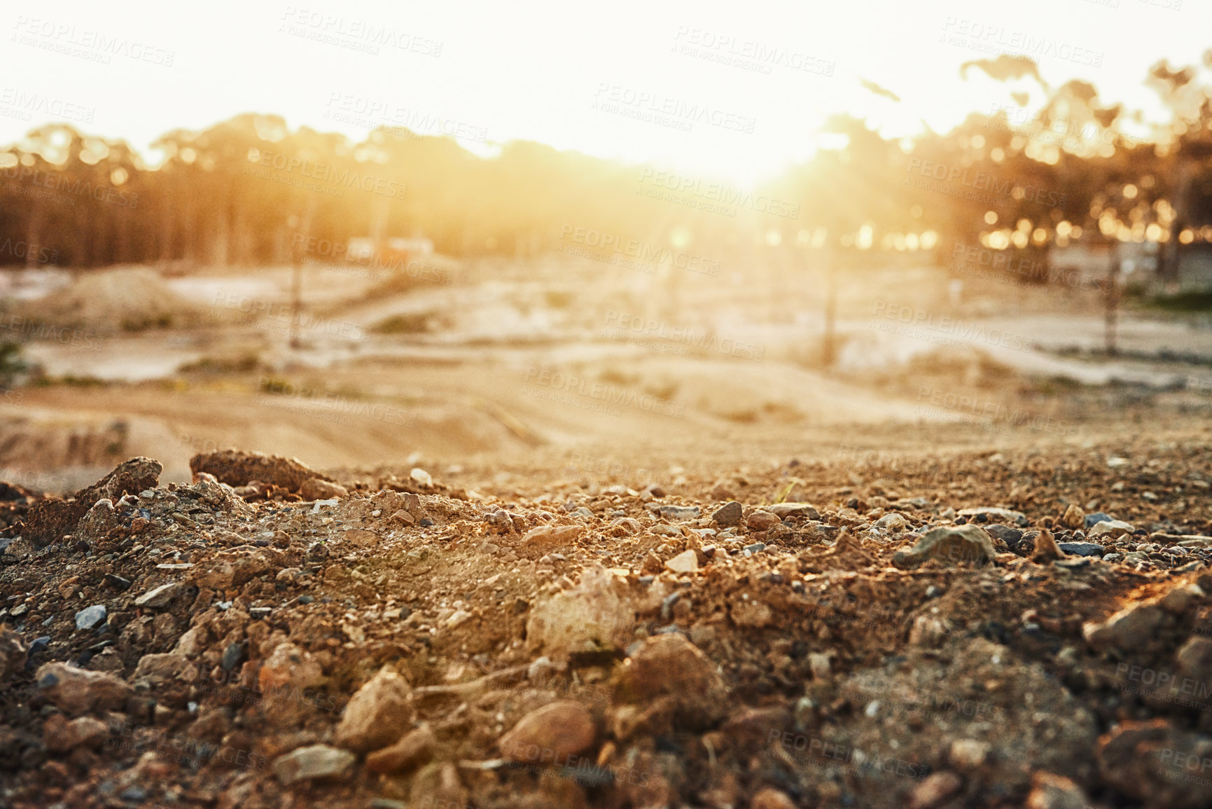 Buy stock photo Sky, sunset and trees in nature with rocks in roadway for outdoor, countryside and lens flare. Landscape, dirt road and tough terrain for extreme sports, competition and sunshine in Switzerland.