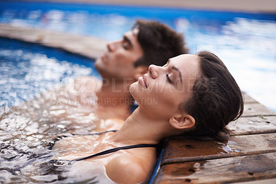 Buy stock photo Shot of an attractive young couple relaxing in a pool