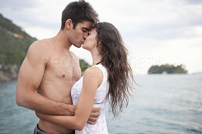 Buy stock photo Summer, holiday and couple kiss by sea in vacation, water and outdoor for date in nature for romance. Partners, woman and man together to travel, journey and adventure in ocean for love with hug 