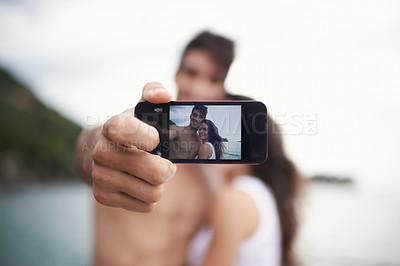 Buy stock photo Phone screen, selfie and happy couple outdoor for vacation, holiday and travel together at ocean. Face, woman and man taking pictures at sea for love, smile or memory in summer by water in nature