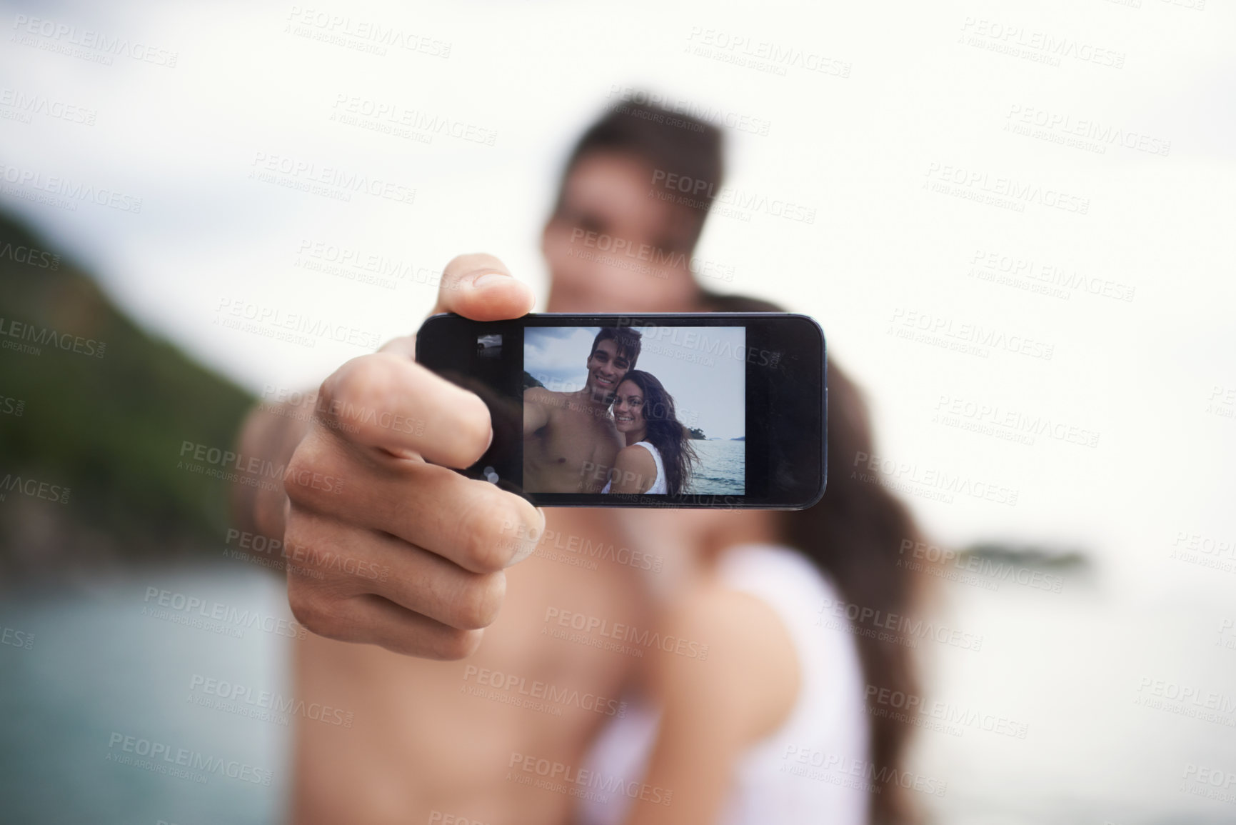 Buy stock photo Phone screen, selfie and happy couple outdoor for vacation, holiday and travel together at ocean. Face, woman and man taking pictures at sea for love, smile or memory in summer by water in nature