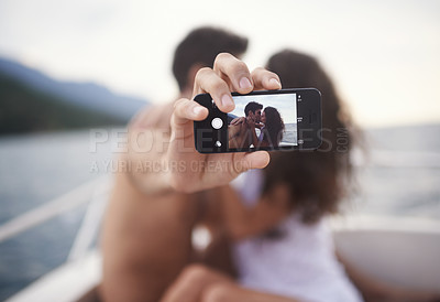 Buy stock photo Shot of an affectionate young couple taking a self portrait while enjoying a boat ride