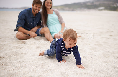 Buy stock photo Happy, baby and parents on beach in sand, summer and family fun with child crawling. Laughing, smile and couple with kid on vacation together for relationship development and nature enjoyment at sea 