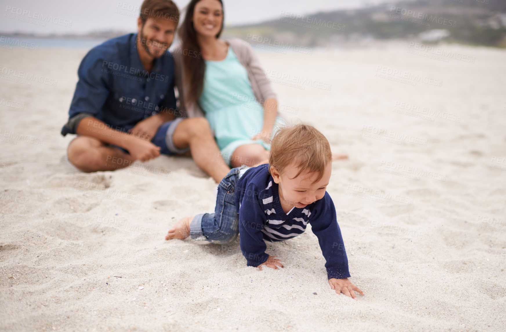 Buy stock photo Happy, baby and parents on beach in sand, summer and family fun with child crawling. Laughing, smile and couple with kid on vacation together for relationship development and nature enjoyment at sea 