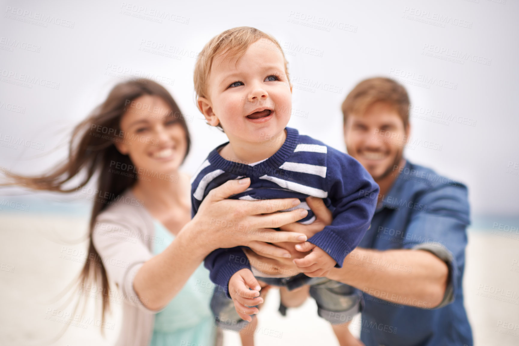 Buy stock photo Cropped shot of a young couple playing with their son at the beach