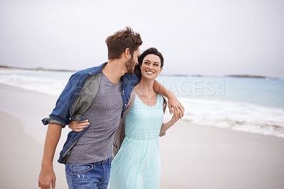 Buy stock photo Cropped shot of a young couple walking along the beach