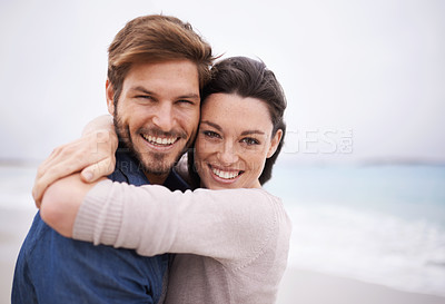 Buy stock photo Cropped portrait of a young couple embracing at the beach