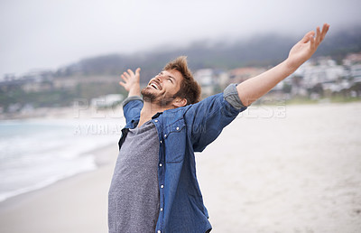 Buy stock photo Shot of a carefree young man throwing his arms back in joy