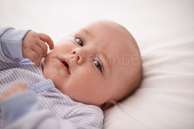 Buy stock photo Baby, bed and cute for portrait, child development and nap time while laying comfortable. Kid, growth and onesie for infant, home and adorable face ready for bed and relaxing with hands and face