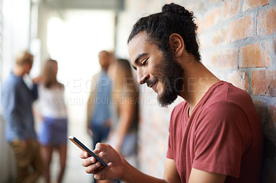 Buy stock photo A young man using a mobile phone with his friends standing in the background