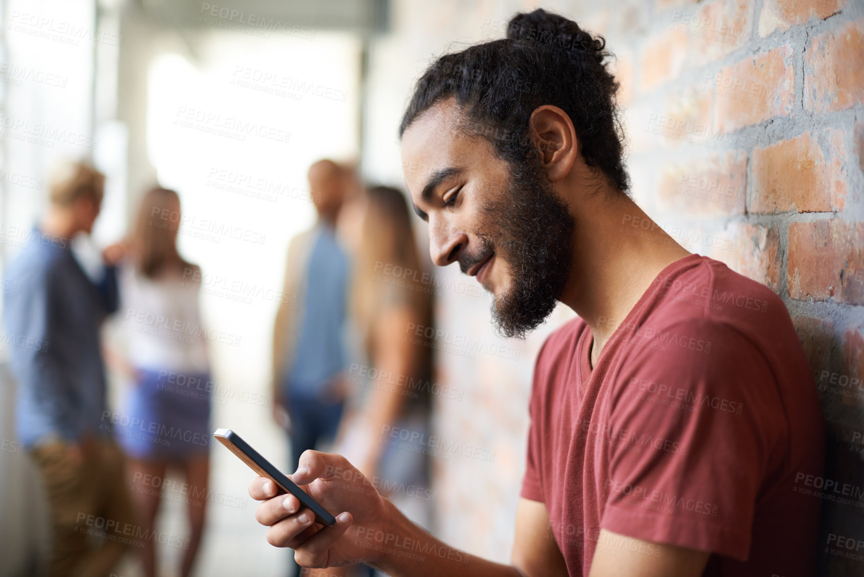 Buy stock photo A young man using a mobile phone with his friends standing in the background