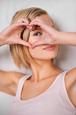 Buy stock photo A cropped portrait of a beautiful young woman making a heart shape with her hands