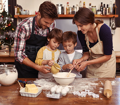 Buy stock photo Two cute little boys baking with their parents in the kitchen